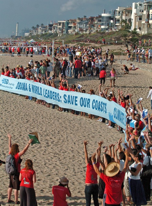 As part of the International Day of Climate Change on Saturday, participants line up and do the tidal wave for an airplane covering the event near the Manhattan Beach Pier. Organizers said 5,200 events were scheduled around the globe to mark the day. (Sean Hiller Staff Photographer)